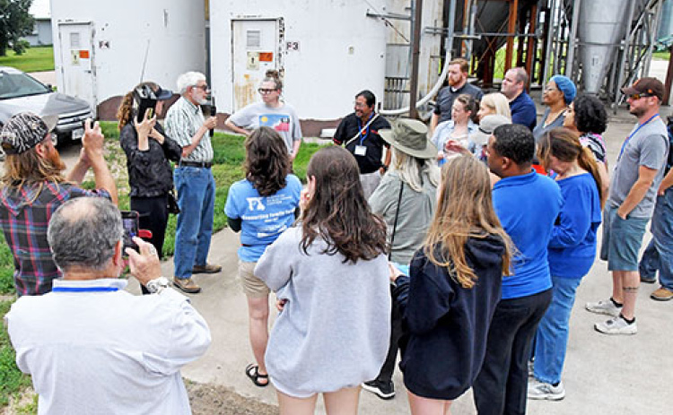 Grain Place Foods President David Vetter (at left holding microphone) speaks to legislators from six states in the surrounding region at a tour of the farm and processing facility near Marquette on June 27.