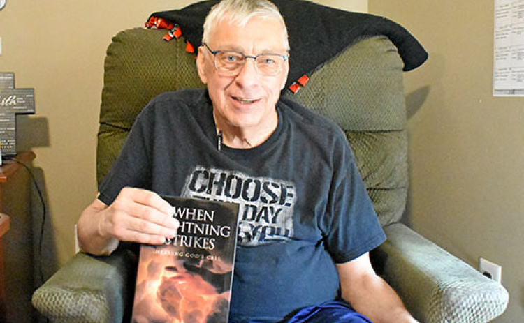 Lonnie Ott sits in his room at Westfield Quality Care holding a copy of his book: “When Lightning Strikes: Hearing God’s Call.” Ott says it took him 10 years to write the book.