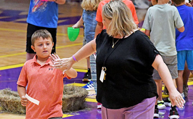 Hampton Elementary Principal Angie Arndt reaches back to give 2nd grader Chance Goertzen a high five after he opens his egg revealing he is a member of the Honorable Family.