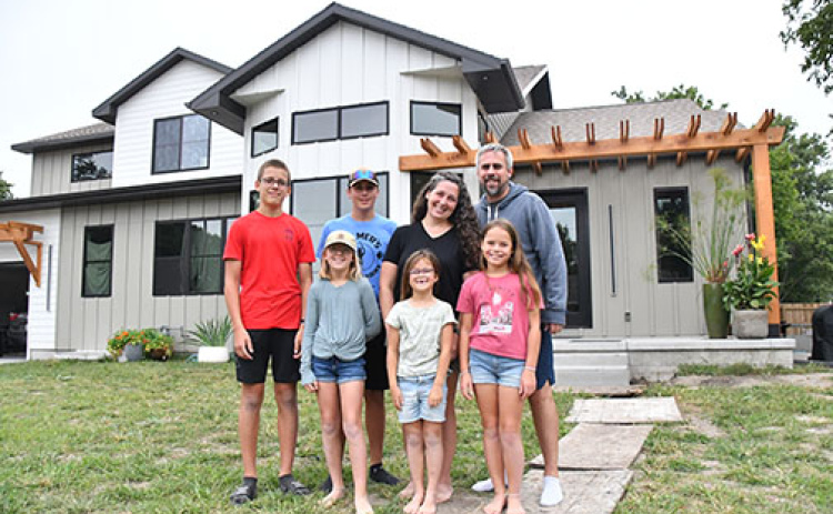 Joseph and Kylee Ochsner stand outside their new five-bedroom home on L Street with their children Gideon, Eden, Boaz, Zipporah and Leah. Pictured below is the fire scene at their home on July 14, 2023.