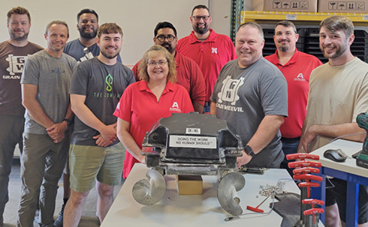 Employees from both the Grain Weevil and Aurora Boardworks display one of the early production models of the visionary robot, parts of which were produced here in Aurora.