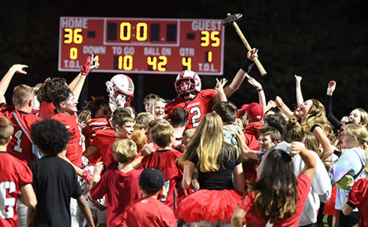 Aurora senior QB Booker Scheierman holds the hammer trophy high as the Huskies and AHS students celebrate defeating rival Grand Island Northwest 36-35 in a wild Homecoming comeback victory Friday. Aurora trailed 28-0 in the first half before scoring the game-winning two-point conversion with 15 seconds left.