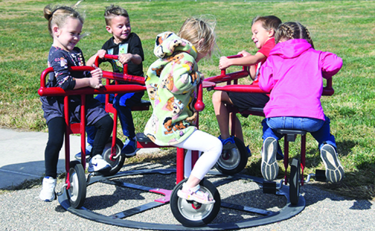 One of the many examples of students benefitting from funding provided through the Aurora Public Schools Foundation is this Merry-go-cycle, which has become a favorite for Aurora preschoolers. Pictured giving it a whirl are, from left: Loralai Farrand, Merrick Reiker, Avery McCartney, Owen Lewis and Benjamin Gomez. The equipment was actually purchased by HCF’s Women in Philanthropy as part of a growing partnership between the two foundations.