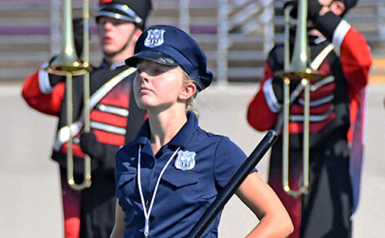 Drum major Savanna James, in costume as a police officer, leads the Aurora Marching Huskies onto the field during Saturday’s field show.