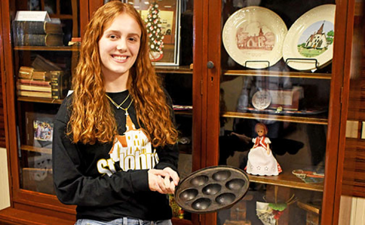 St. John’s church member Jasmine Hansen displays a vintage cast-iron aebleskiver pan belonging to Becky Richter. The unique pan was handed down from Richter’s Danish grandmother.