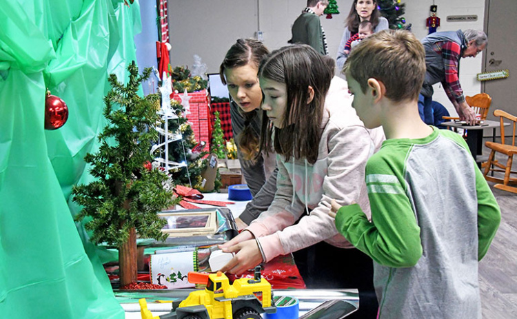 Lily Francl (center) presses a button that unlocks a tool for the escape room’s next puzzle. With her is aunt Kim Bossert and Lily’s brother Nolan.