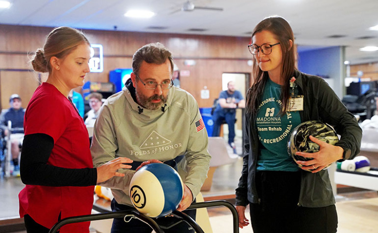 Therapists at Madonna Rehabilitation Hospital in Lincoln use a bowling ball to help Ryan Goertzen recover the use of his right arm.