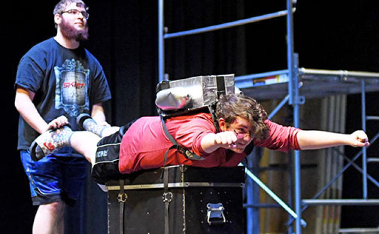 Patrick Star, played by Jacob Inman (center) blasts off with a jetpack for a scene in Aurora High School’s production of “The SpongeBob Musical” during a rehearsal on Friday. Giving Inman a boost during rehearsal is James Dieckmann.
