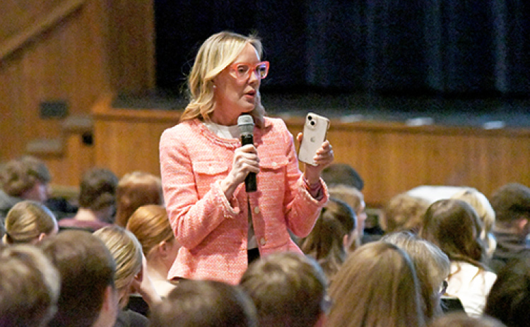 Aurora High School Health and Wellness Day speaker Suzie Fogarty holds up her iPhone to make a point during her keynote address to high school students last Wednesday. Fogarty reported that today’s high school students spend an average of 7-1/2 hours a day looking at screens, and that’s on top of the time computers are used for study.