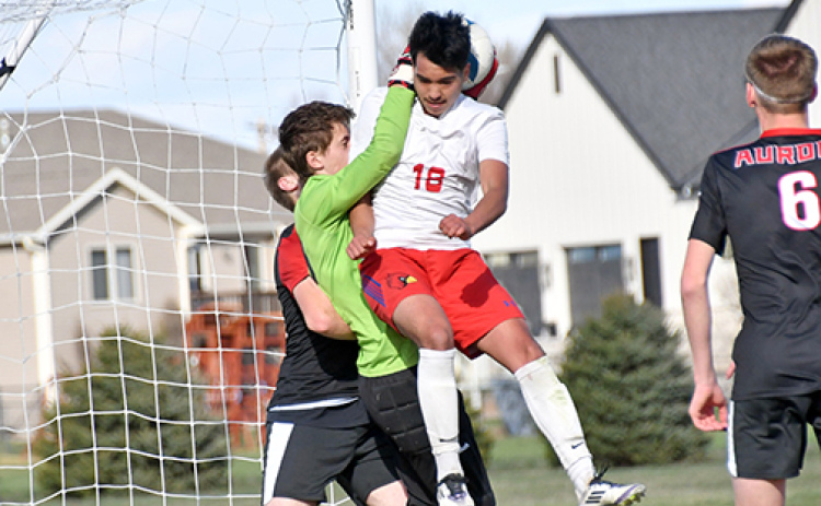 Aurora’s backup keeper Calvin Miller catches both the soccer ball and Crete’s Alfredo Herrera in the air at the net during the Huskies’ 5-2 loss to the Cardinals Thursday.