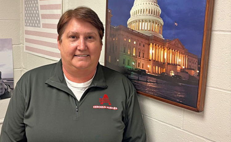 American history teacher Brenda Klawonn stands in front of a photo from Washington D.C., a city she visited 15 times as part of student projects like Heroes & Huskies.