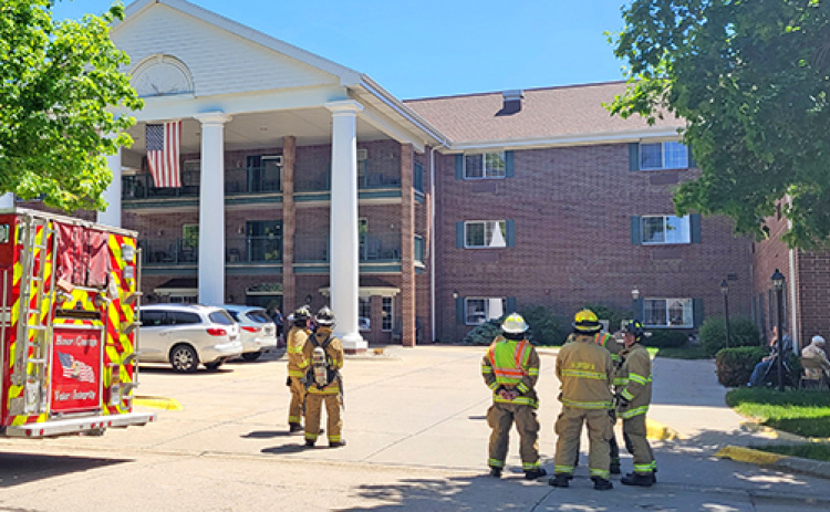 Firefighters and residents wait outside East Park Villa on Tuesday afternoon while fire officials inside the building seek out the source of an alarm that had sounded, prompting an evacuation of residents and staff.