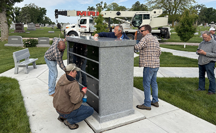 Members of the installation crew polish the new columbine unit after hoisting it into place at the Aurora Cemetery June 4.