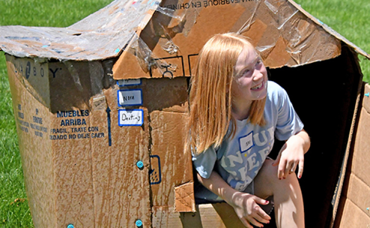 Cardboard Creations camper Nora Tompkins rises from her cardboard house after it withstood assaults of water, ice and wind.