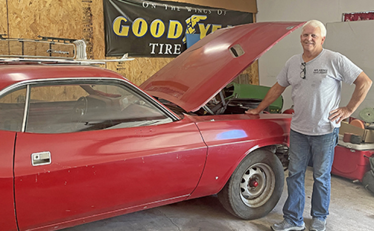 Bill Gowen stands next his red 1970 Dodge Challenger in his garage in Aurora. He originally bought and modified the car in high school and is excited to restore it in coming days.