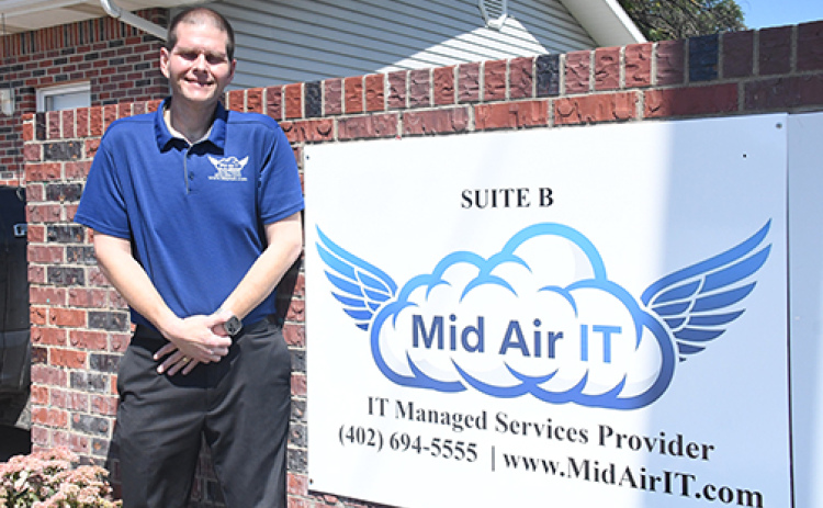 Scott Peters, one of three partners involved in the new Mid Air IT business venture in Aurora, stands by the Highway 14 sign by the new office location at 207 S. 16th St.