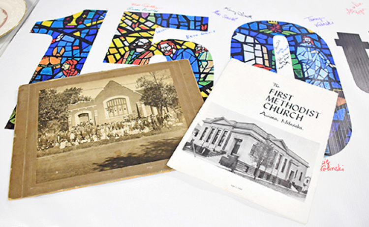 Several tables in the fellowship hall of the Aurora United Methodist Church display photos and other historical artifacts from the church’s 150-year history. At left above are photos of the original church buildings of the Evangelical United Brethren and First Methodist churches that united in the 1970s to form the current United Methodist congregation.