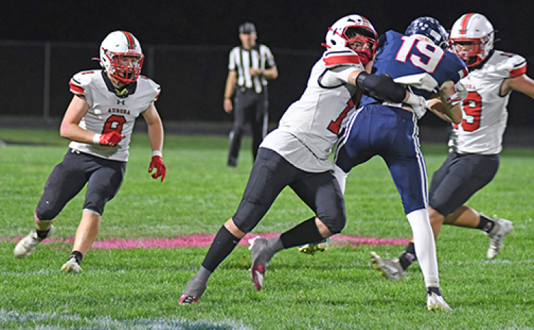 Junior Hudson Decker puts a hit on the Patriots’ Nick Mousel during Friday’s game at Adams Central.