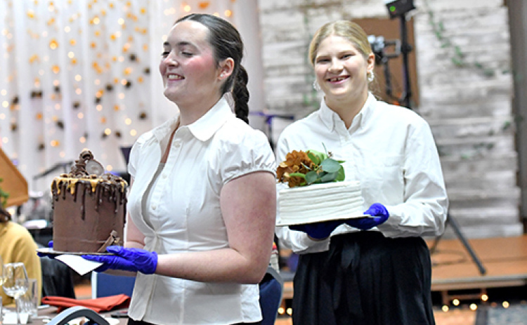 Adelynne Hendrickson and Violet Carstensen walk around tables showcasing the cakes in the Harvest Gala’s dessert auction Saturday night.