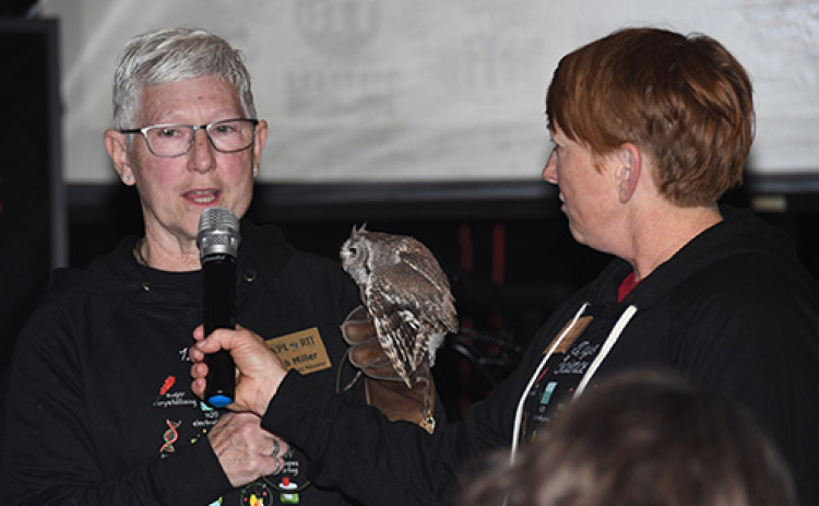 Deb Miller, left, holds one of the Edgerton’s winged friends as she explains a raptor experience being auctioned off. At right is Mary Molliconi.