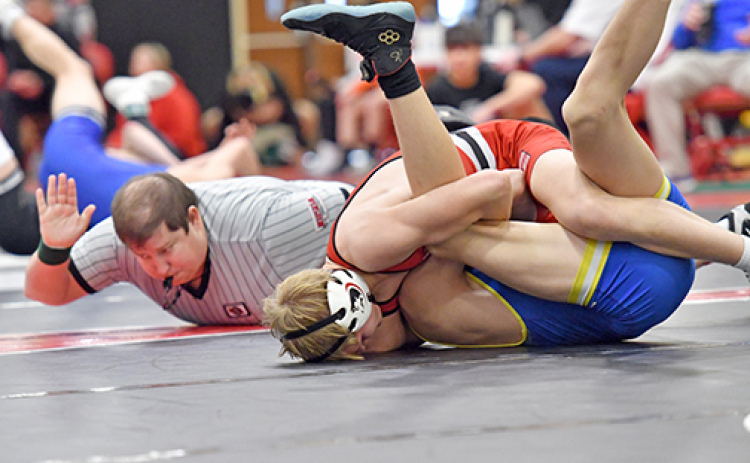 Carson Krejci, shown above getting the pinfall win, was one of three gold medalists for the Huskies at Saturday’s Central Conference tournament. At right, Logan Svoboda became a three-time conference champ with his tournament win Saturday.