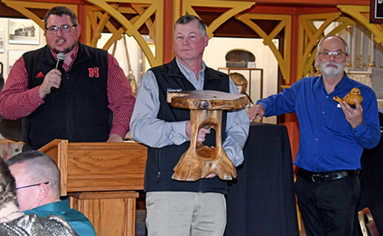 Auctioneer Jamie Bergmark, left, calls for bids during Monday’s live auction at the Plainsman, while volunteers Greg Bonifas and Eric Lohrmeyer assist.