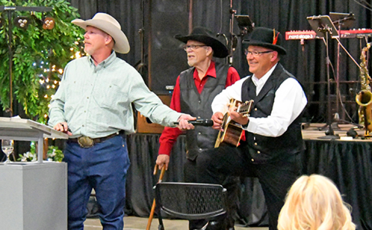 Harlan Schafer, right, plays a guitar he made especially for Friday’s Memorial Foundation auction. The item drew a winning bid of $2,200. Pictured with Schafer are auctioneers Mark and Kelly Kliewer.