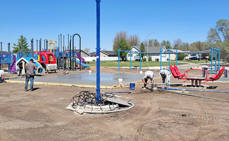 Workers pour a concrete walkway that will go through the middle of the Hamilton County Inclusive Playground. At right in the background is the framework for the zipline that will allow disabled children to ride next to their able-bodied friends.