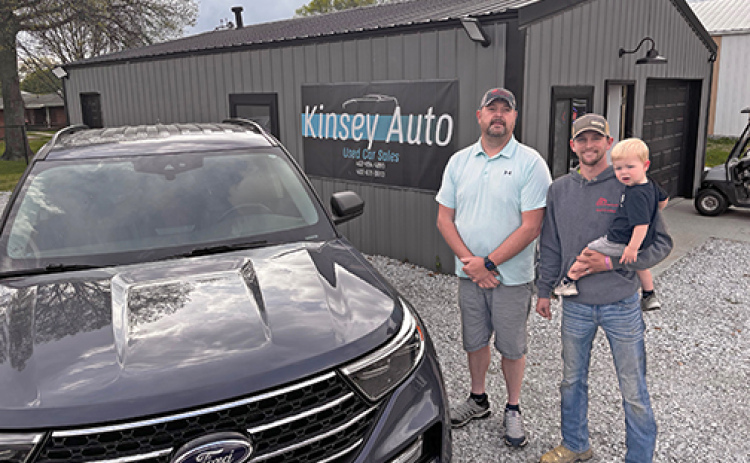 Rich Kinsey, left, poses with his son Kody Bengston and grandson Tatum on the new Kinsy Auto used car lot located along Highway 34 in Aurora.