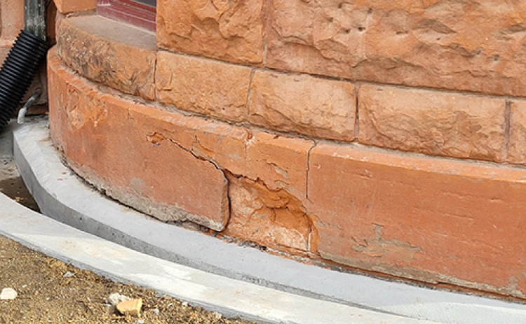 These deteriorating foundation stones on the curving bow bay window portion of the south side of the courthouse will be replaced soon following action by the county commission on Monday. The Colorado sandstone blocks have been weakened by water that has seeped into them over the years. That problem is being corrected by the concrete ground level gutter system that is being installed and which can be seen at the bottom of the photo.
