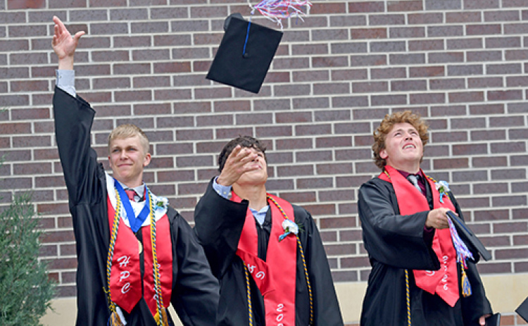 From left, HPC seniors Brodey Spurling, Levi Russell and Chase Owens toss their caps into the air after officially becoming Storm graduates Saturday afternoon.