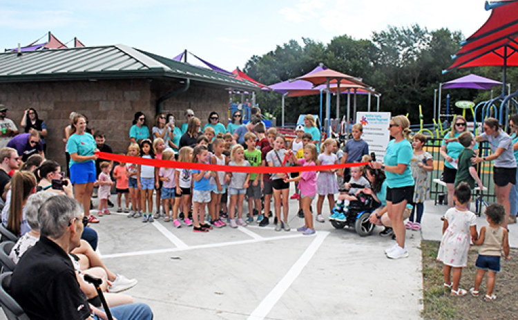 A group of children prepares to cut the ribbon to officially open the Hamilton County Inclusive Playground on Saturday morning.