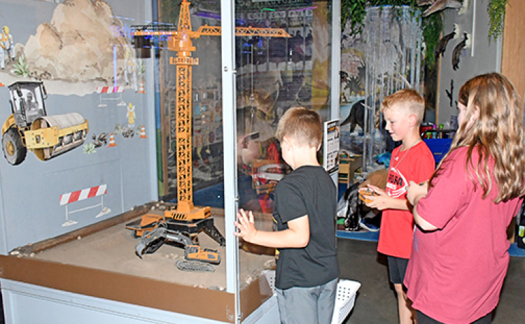 Visitors can move toy vehicles using remote controls in one of the exhibits in Edgerton’s new Build Zone. Pictured from left are Hayes Beins, Calvin Shannon and Destiny Almont.