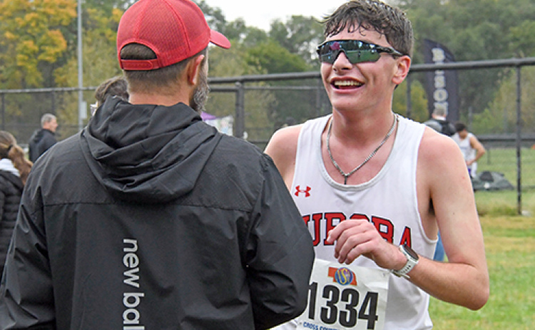 Grayson Oswald shares a moment with Aurora coach Tony Sigler after becoming the champion runner in the C4 district last week. Oswald laughs over how he broke his shoe during the second half of the race.