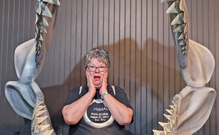 Patti Kell poses for a picture inside the jaws of a massive ancient shark at a fossil museum in Aurora, N.C.