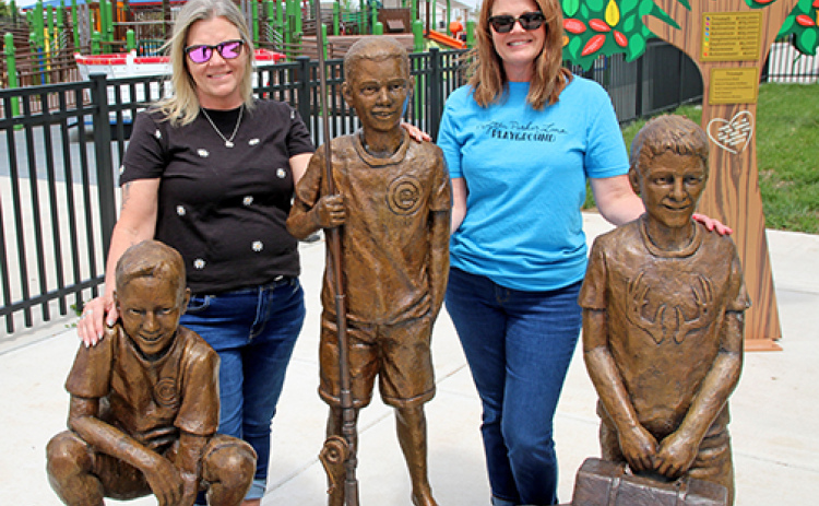 Julie Hoffman, left, and April McDaniel are pictured outside the Peyton Parker Lane Playground in York next to statues of their late sons for whom the inclusive playground is named. The women and their husbands were members of the group that founded the facility which opened in 2023.