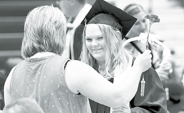 Hampton senior Logan Nissen presents a flower to her mother, Amy, during Saturday’s graduation ceremony. News-Register/Kurt Johnson