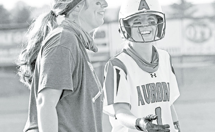 Aurora senior Kylie Larson shares a light moment with Aurora coach Ashton Voss after sliding safely into third base during the Lady Huskies’ 10-3 win over Holdrege Thursday. News-Register/Richard Rhoden
