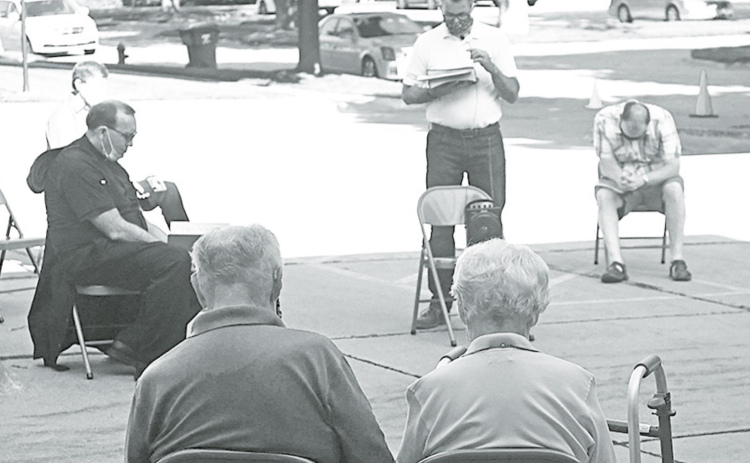 Pastor Bob Gannon (center) takes a moment to share a prayer with the residents for the community of Aurora. News-Register/Jeni Moellenberndt