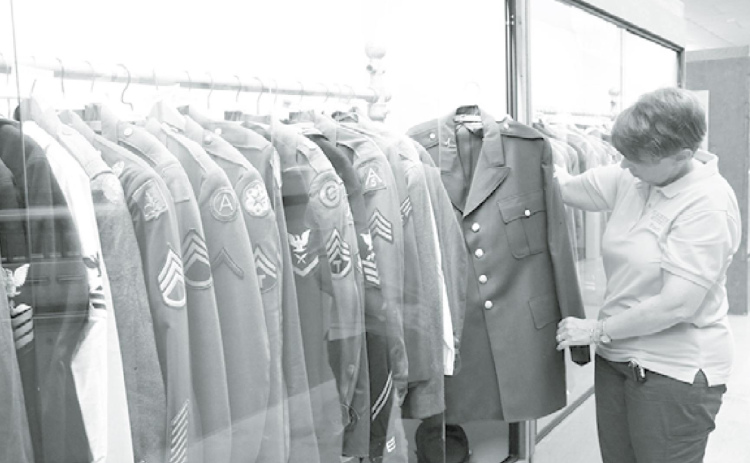 Plainsman Museum executive director Tina Larson is fond of the military jacket exhibit due to its wide array of years, patches and branches. She is seen here with Roger Luthy’s jacket. News-Register/Cheyenne Rowe