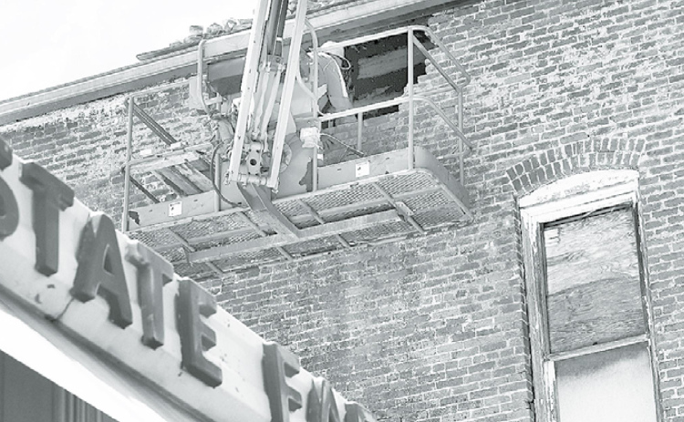 Work crews have been busy repairing a damaged portion of the east wall of the Jones Building, where bricks had fallen away in late January causing damage below. News-Register/Kurt Johnson