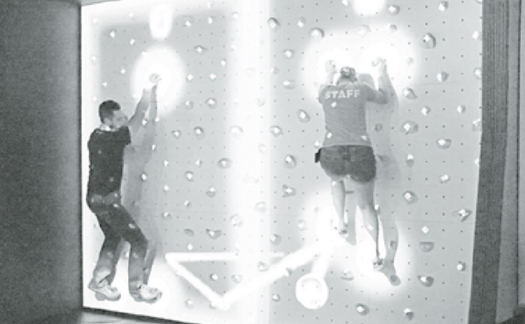 Edgerton Mad Scientist John Boeder (left) squares off against educator Nicole Havlik on the Edgerton’s popular augmented reality climbing wall. There are often new games to enjoy. News-Register/Cheyenne Rowe