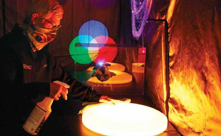 Edgerton educator Deb Miller takes a minute when the Edgerton is without guests to sanitize objects inside the new ‘laser island’ exhibit. News-Register/Cheyenne Rowe