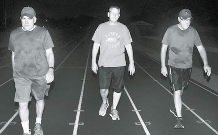 Pictured from left, Kelly Grossnicklaus, Jeff Bart and Todd Jensen walk on the AHS track Friday, the 20th anniversary of when the daily 3-mile routine began. News-Register/Kurt Johnson